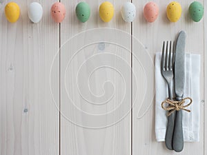 Easter eggs, vintage cutlery and napkin on wooden board. table set