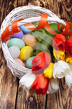 Easter Eggs in a white basket with colorful tulips