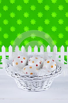 Easter eggs in the basket on patterned background