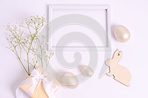 Easter eggs, wooden hare, gepsophila flowers, wooden hare, gift box near the frame on a white background