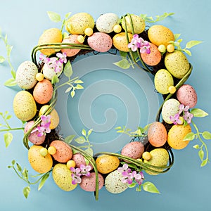 Easter eggs wreath on light blue background