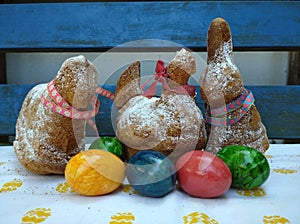 Easter ewe lamb, hen and bunny baked and real hard cooked eggs in colors. In front of the blue wood and on the easter