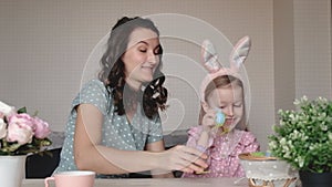 Easter, family, holiday and children concept. Mother and daughter playing with Easter eggs. Happy family preparing for