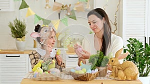 Easter family traditions. Mom and daughter are playing with colorful eggs in the kitchen, enjoying the holiday, the