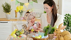 Easter family traditions. Mom and daughter are playing with colourful eggs in the kitchen, enjoying the holiday, the