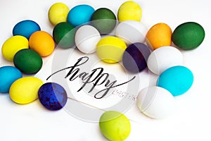 Easter festive colorful eggs on a white background with a greeting card calligraphy `happy easter`. eggs yellow, blue