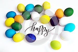 Easter festive colorful eggs on a white background with a greeting card calligraphy `happy easter`. eggs yellow, blue, green