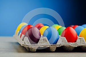 Easter festive multicolor eggs carton, blue background