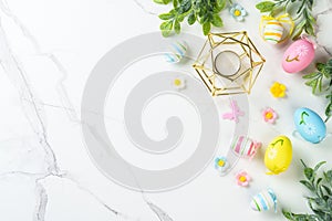 Easter composition with colored eggs and green plants on white background.
