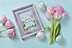 Easter flat lay with bunch of pink tulips and greeting card in a frame