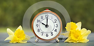 Easter flowers and alarm clock, spring forward, daylight savings time concept