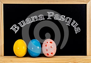 Easter frame with painted eggs and chalkboard. Happy Easter in white chalk. Happy Easter in italian : buana pasqua photo