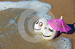 Easter funny eggs under umbrella on a beach