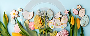 Easter gingerbread cookies, spring flowers on blue background. Cozy home Easter greeeting card concept, banner for your site, copy