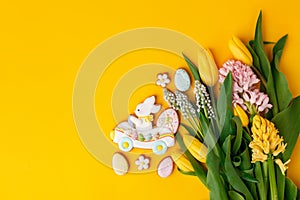 Easter gingerbread with icing, seasonal flowers on yellow table, festive Easter background web banner, copy space. Seasonal