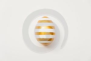 Easter golden with striped patternd egg isolated on white background. Minimal easter concept. Happy Easter card with copy space