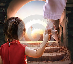 Easter and Good Friday concept, Jesus holding child's hand with empty tomb of Jesus Christ at cross on sunset background