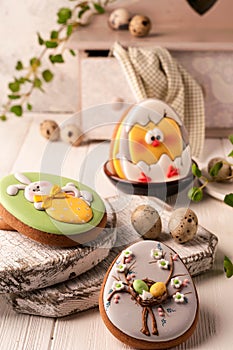 Easter green cookies with painted easter bunny and hatched chicken near quail eggs, decorative buffet and napkin