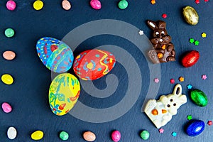 Easter greeting card with colorful candy frame and Easter egg, chocolate bunny and eggs