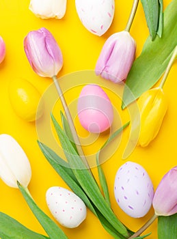 Easter greeting card. Multicolored easter eggs and tulips on yellow background. Easter concept