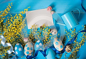 Easter greeting card. Painted eggs with yellow mimosa flowers and tiny watering can
