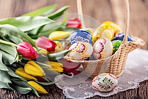 Easter. Hand made painted easter eggs in basket and spring tulips