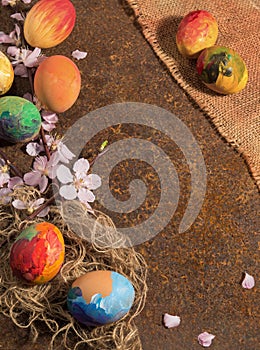 Easter hand-painted eggs and fringed jute canvas,almond blossom and petals,arranged on rusty rustic texture.