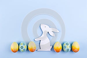 Easter holiday background with eggs. Top view of colorful painted chicken eggs plased in a row and decorative bunny