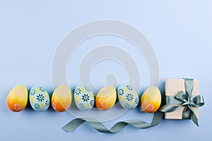 Easter holiday background with eggs. Top view of colorful painted chicken eggs plased in a row and present box