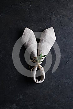 Easter holiday background.Top view of bunny ears linen napkin on dark rusty background. Copyspace