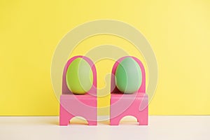 Easter holiday concept with cute eggs life. Different emotions and feelings. Lovely couple eggs sitting on pink chairs