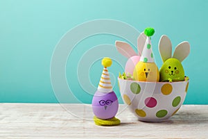 Easter holiday concept with cute handmade eggs, bunny, chicks and party hats in bowl