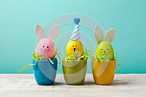 Easter holiday concept with cute handmade eggs, bunny, chicks and party hats in cup