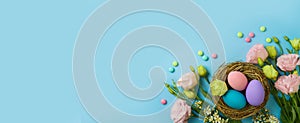 Easter holiday concept with easter eggs and spring flowers on blue background. Top view, flat lay