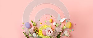 Easter holiday concept with easter eggs and spring flowers on pink background. Top view, flat lay