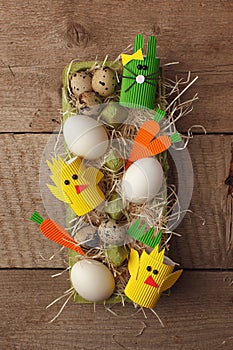 Easter holiday concept with eggs, cute handmade bunny, chicks in papaer box for egg on wooden table, sptingtime background