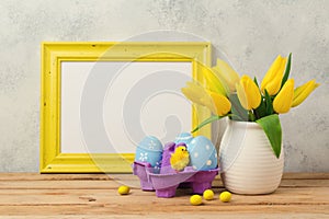 Easter holiday concept with tulip flowers, eggs decorations and blank photo frame
