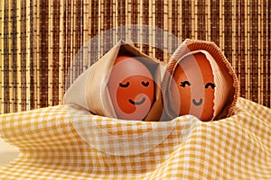 Easter Holiday Concept Two Egg Hooded Smile on a Yellow Napkin with Dark Brown Texture Background