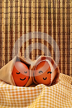 Easter Holiday Concept Two Egg Hooded Smile on a Yellow Napkin with Dark Brown Texture Background Vertical
