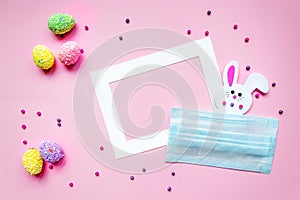 Easter holiday creative pink background with white frame for text, Easter decoration bunny hiding behind a mask, colored painted