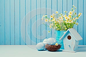 Easter holiday decoration with daisy flowers, eggs and birdhouse