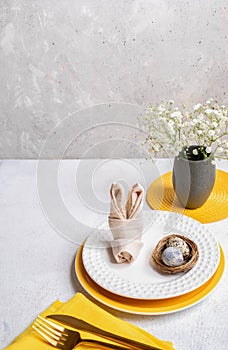 Easter holiday image of table serving idea. Table decoration in white and yellow colors of tableware
