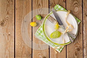 Easter holiday table setting with plate and eggs decoration on wooden background.