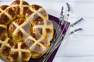 Easter hot cross buns with lavender flowers, chocolate eggs on napkin and wooden white table.