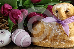 Easter lamb cake with purple ribbon, easter eggs and tulips flower
