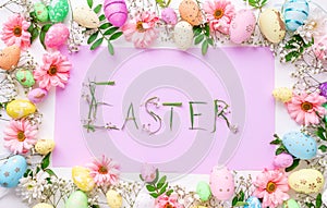 Easter letters made of grass in a frame of colorful eggs and flowers. Easter background, template for design