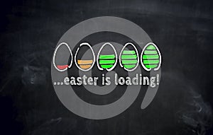 Easter is loading concept with eggs on blackboard