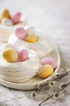 Easter meringue nests with colorful sweet eggs on plate.