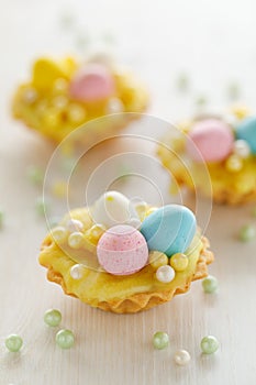 Easter mini tarts decorated with frosting and marzipan eggs in pastel colors