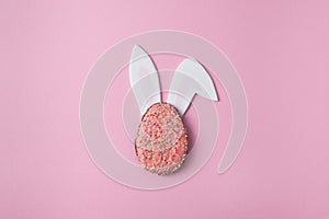 Easter minimalist layout Easter egg cookie with bunny ears Easter concept on a pink background top view